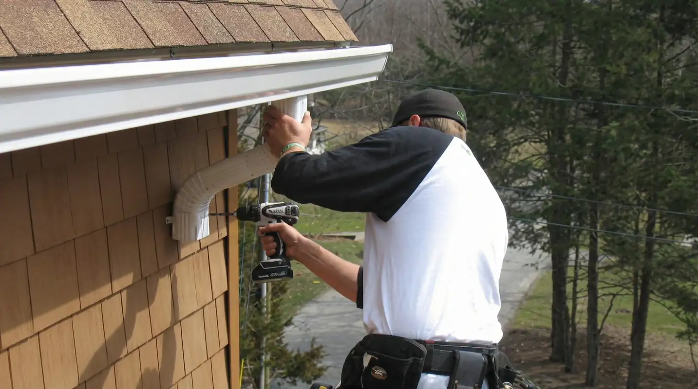 Professional contractor installing tan vinyl siding panels on a residential home exterior in Sioux Falls, SD